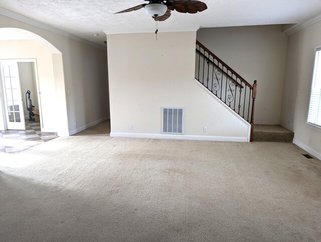 unfurnished living room featuring stairs, carpet flooring, visible vents, and crown molding