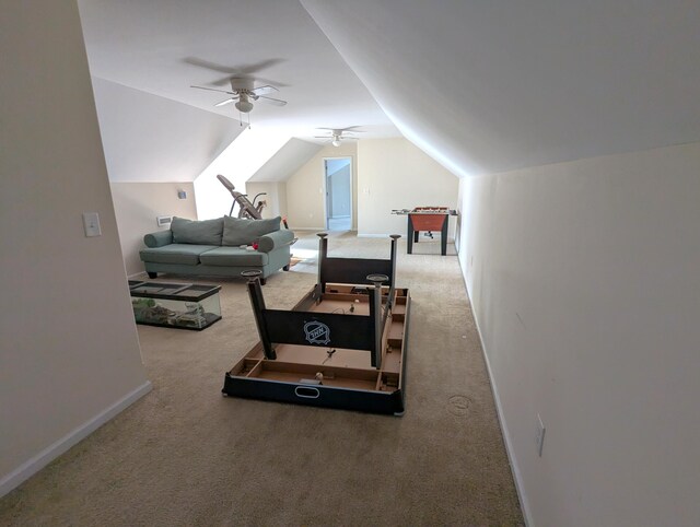 interior space with vaulted ceiling, carpet flooring, a ceiling fan, and baseboards