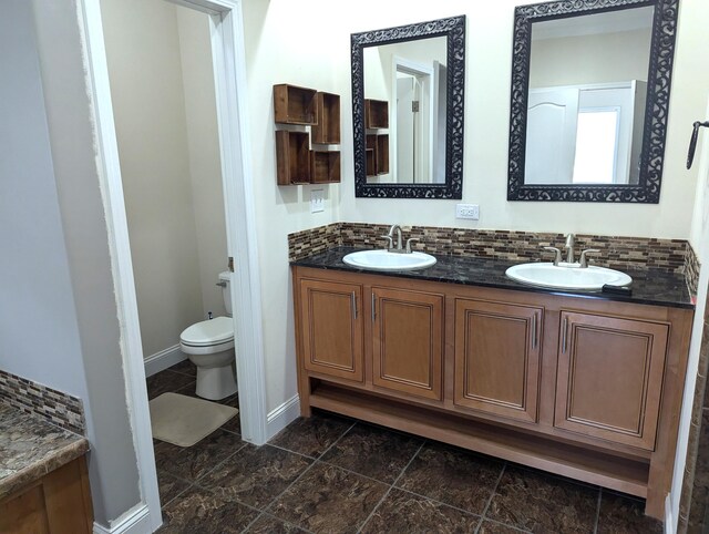 full bath featuring baseboards, a sink, backsplash, and toilet