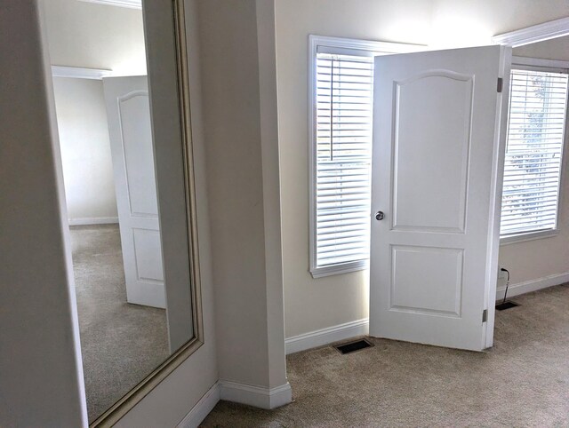 entryway with baseboards, visible vents, and carpet flooring