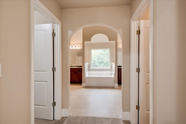 2083 Willhaven Dr, Augusta, GA 30909 - hallway featuring arched walkways, light carpet, baseboards, and a sink