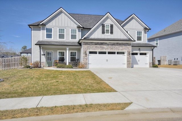 craftsman house with a garage, stone siding, fence, board and batten siding, and a front yard