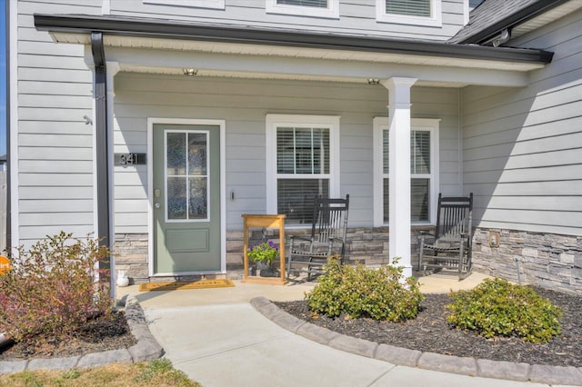 entrance to property featuring a porch and stone siding