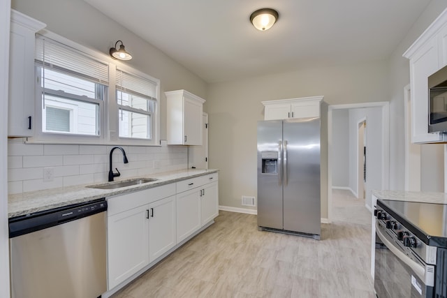 807 Crawford Ave, Augusta, GA 30904 - kitchen with appliances with stainless steel finishes, a sink, white cabinets, decorative backsplash, and light stone countertops