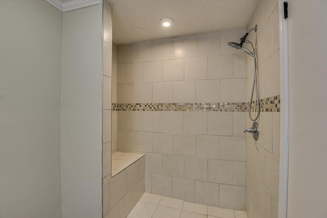 bathroom featuring crown molding, tiled shower, and tile patterned flooring