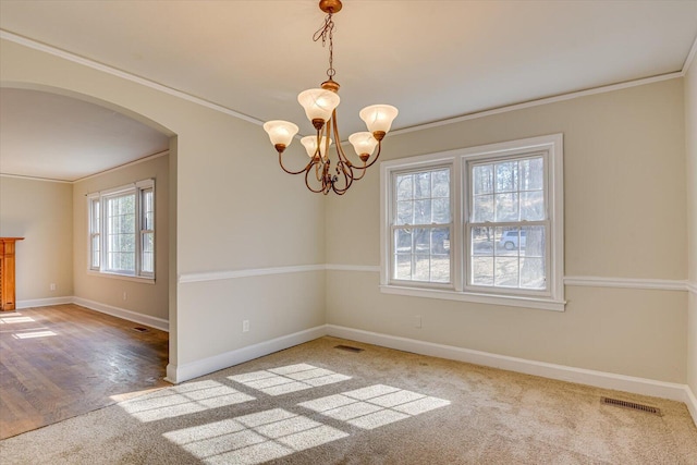 carpeted empty room featuring a notable chandelier and crown molding