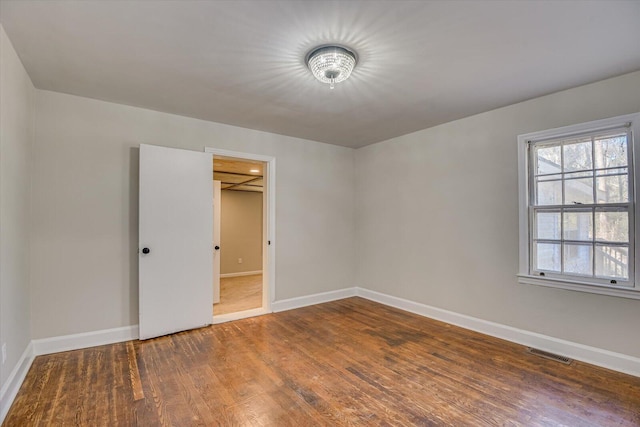 unfurnished bedroom featuring dark wood-type flooring, a walk in closet, and a closet