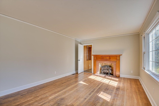 unfurnished living room with ornamental molding, a brick fireplace, and light wood-type flooring