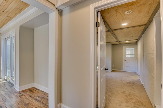 corridor featuring brick wall, light colored carpet, and wood ceiling