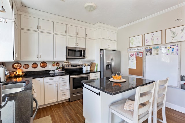 kitchen with dark wood-style floors, appliances with stainless steel finishes, ornamental molding, white cabinetry, and a sink