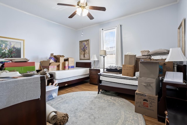 bedroom featuring wood finished floors, a ceiling fan, and crown molding