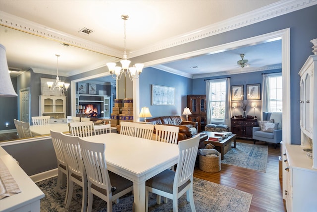 dining area featuring dark wood-style floors, visible vents, ornamental molding, and a multi sided fireplace