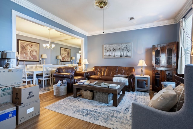 living room with ornamental molding, wood finished floors, visible vents, and a notable chandelier