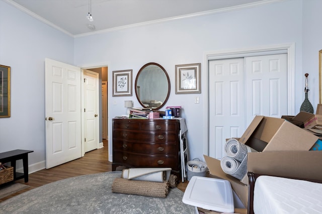 bedroom featuring a closet, crown molding, baseboards, and wood finished floors