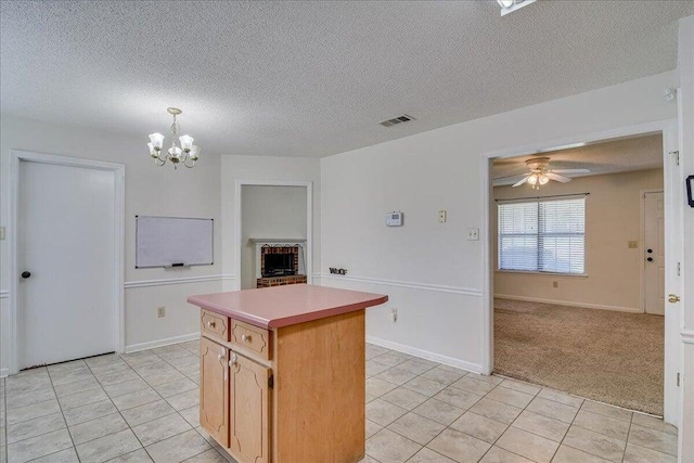 kitchen with ceiling fan with notable chandelier, a kitchen island, light colored carpet, and a textured ceiling