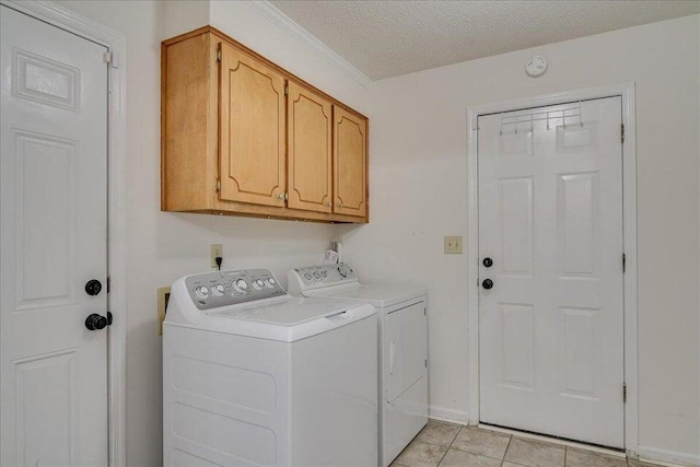 laundry area with cabinets, light tile patterned floors, a textured ceiling, and washer and clothes dryer