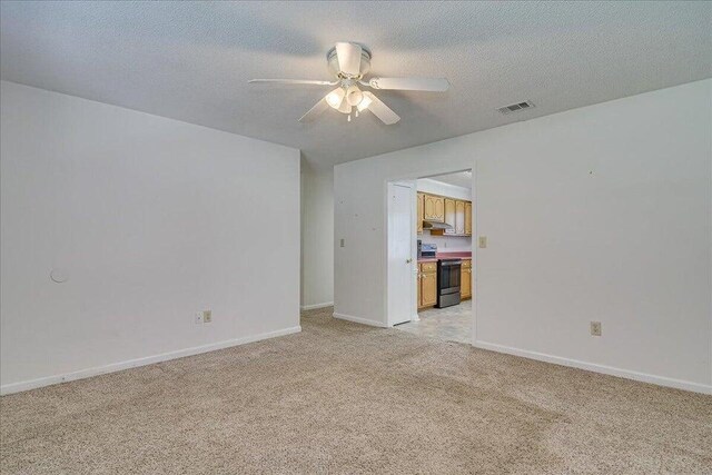 unfurnished room featuring a textured ceiling, ceiling fan, and light carpet