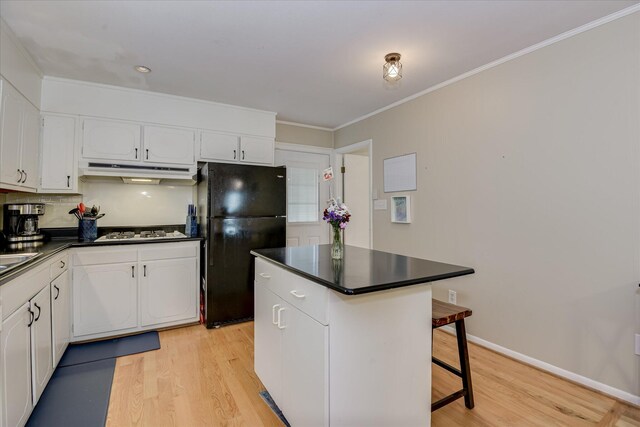 2408 Forest Park Rd, Augusta, GA 30904 - kitchen featuring freestanding refrigerator, under cabinet range hood, dark countertops, light wood-type flooring, and white gas stovetop