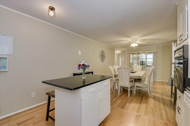 2408 Forest Park Rd, Augusta, GA 30904 - kitchen featuring dark countertops, crown molding, a breakfast bar, a kitchen island, and white cabinetry