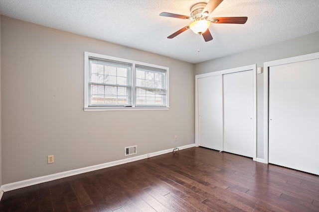 2901 Sussex Rd, Augusta, GA 30904 - unfurnished bedroom with two closets, dark wood-type flooring, baseboards, ceiling fan, and a textured ceiling