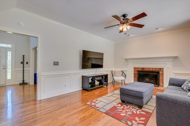819 Cape Cod Ct, Evans, GA 30809 - living room with ornamental molding, wood finished floors, ceiling fan, a brick fireplace, and a wainscoted wall