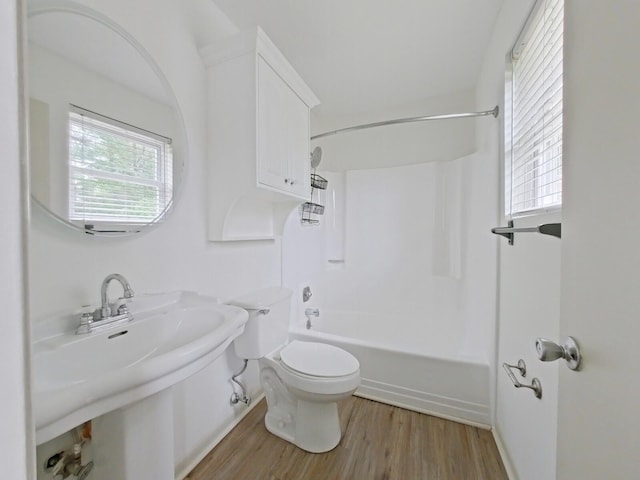 bathroom with a sink, wood finished floors, bathing tub / shower combination, and toilet