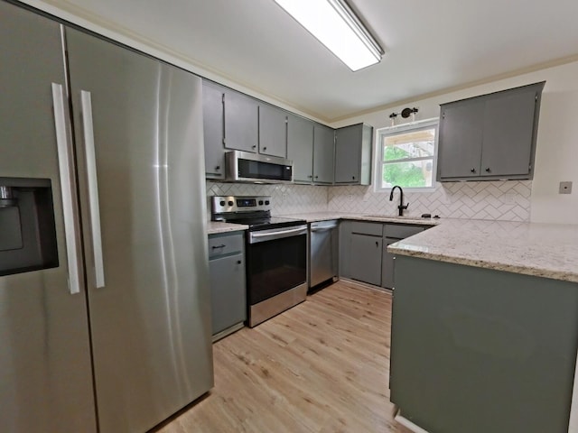 kitchen featuring gray cabinetry, appliances with stainless steel finishes, and light wood-style flooring