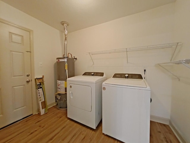 washroom with laundry area, light wood-style floors, baseboards, washing machine and clothes dryer, and water heater