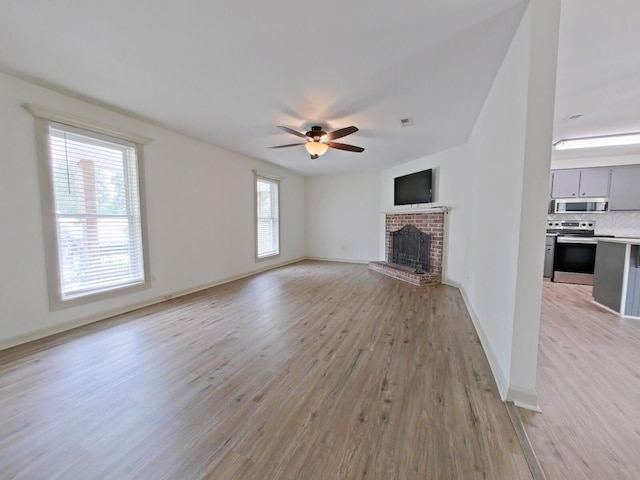 unfurnished living room featuring baseboards, a ceiling fan, light wood-style flooring, and a fireplace