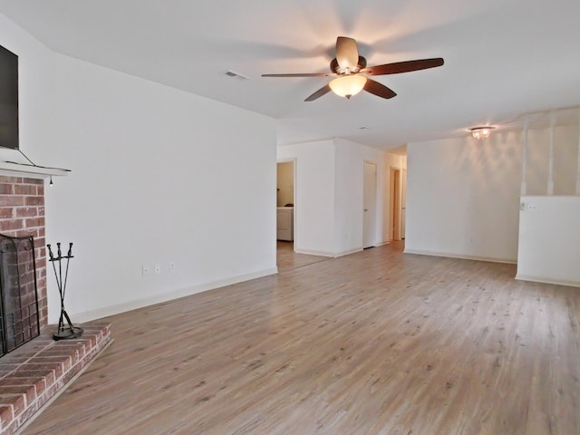 unfurnished living room with ceiling fan, a fireplace, light wood finished floors, and visible vents