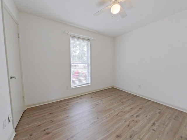 empty room with baseboards, a ceiling fan, and light wood finished floors