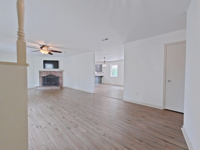 unfurnished living room featuring baseboards, a ceiling fan, wood finished floors, and a fireplace