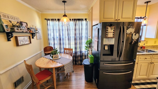 kitchen featuring ornamental molding, refrigerator with ice dispenser, visible vents, and a sink