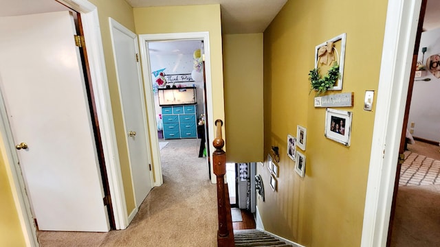 corridor with an upstairs landing and carpet flooring