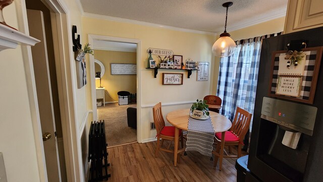 dining room featuring a textured ceiling, dark wood-type flooring, and ornamental molding