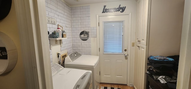 laundry area featuring cabinets, washing machine and dryer, and hardwood / wood-style flooring