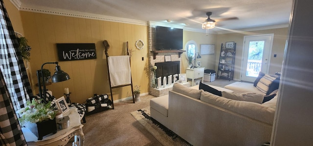 living room with wood walls, ornamental molding, carpet flooring, ceiling fan, and a fireplace