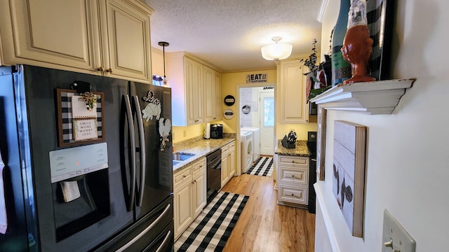 kitchen featuring separate washer and dryer, black appliances, a textured ceiling, cream cabinets, and light wood-type flooring