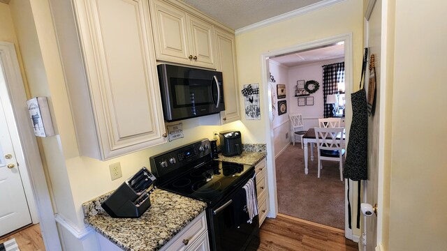 kitchen featuring pendant lighting, light hardwood / wood-style flooring, ornamental molding, stone countertops, and black fridge