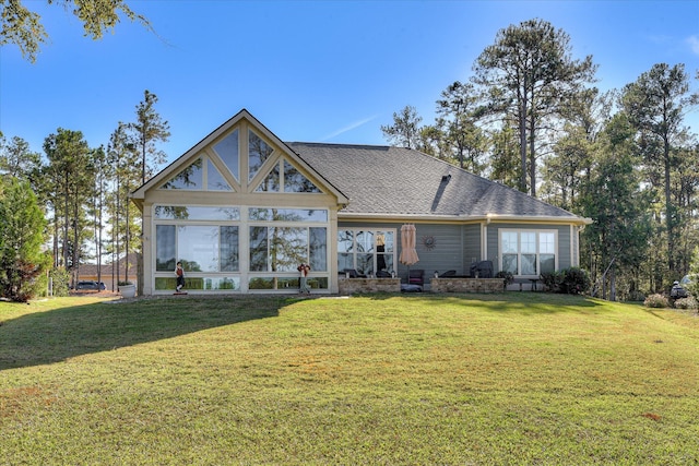 back of property featuring a lawn and roof with shingles