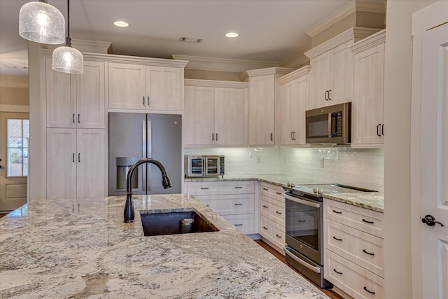 kitchen with crown molding, a sink, pendant lighting, appliances with stainless steel finishes, and light stone countertops