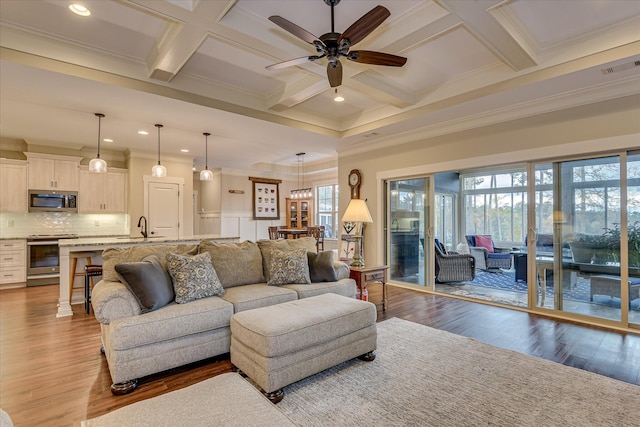 living area with ceiling fan, coffered ceiling, and crown molding