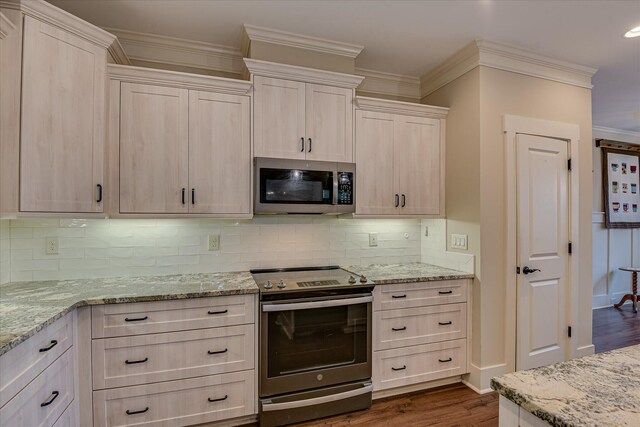 kitchen with dark wood-type flooring, crown molding, light stone countertops, and appliances with stainless steel finishes