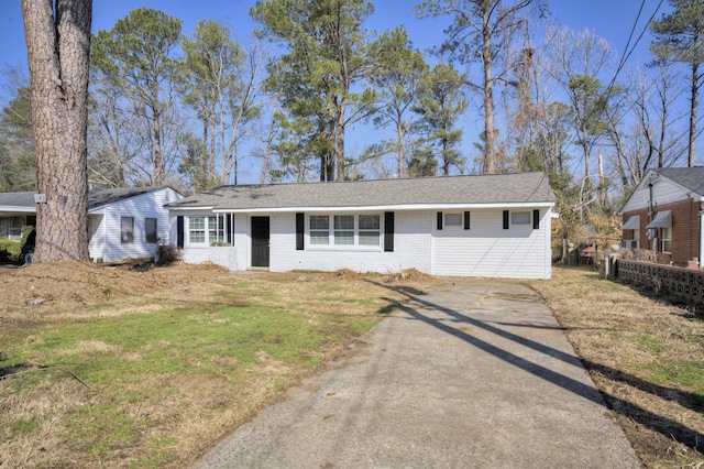 view of front of home featuring a front yard, brick siding, driveway, and fence