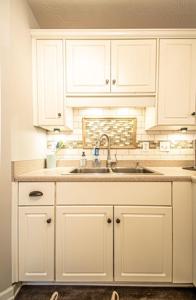 kitchen with tasteful backsplash, white cabinets, and a sink