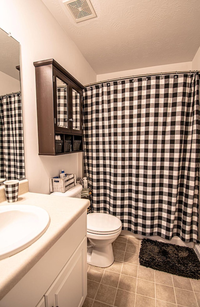 bathroom with a textured ceiling, tile patterned flooring, toilet, vanity, and visible vents