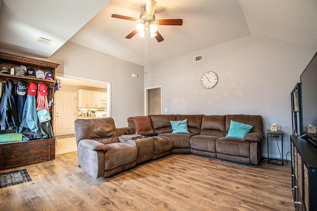 living area with light wood finished floors, visible vents, and vaulted ceiling