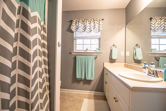 full bath featuring a textured ceiling, tile patterned flooring, a shower with shower curtain, vanity, and baseboards