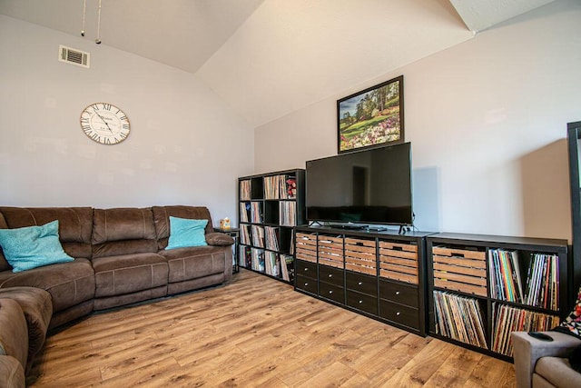 living room featuring visible vents, vaulted ceiling, and wood finished floors