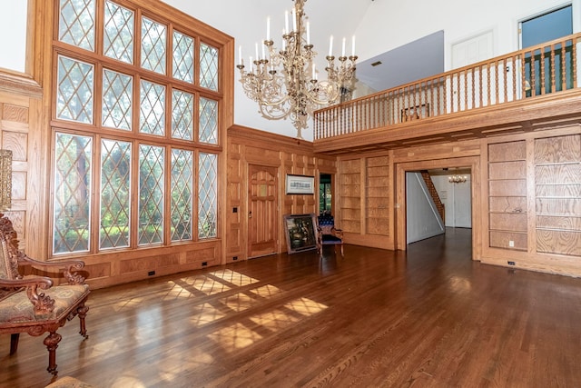 506 Regent Pl, Augusta, GA 30909 - unfurnished living room featuring built in shelves, wood walls, a towering ceiling, stairs, and wood finished floors